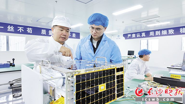 项军华（左）和技术人员在检查新的卫星。长沙晚报实习生 李佳峰 摄